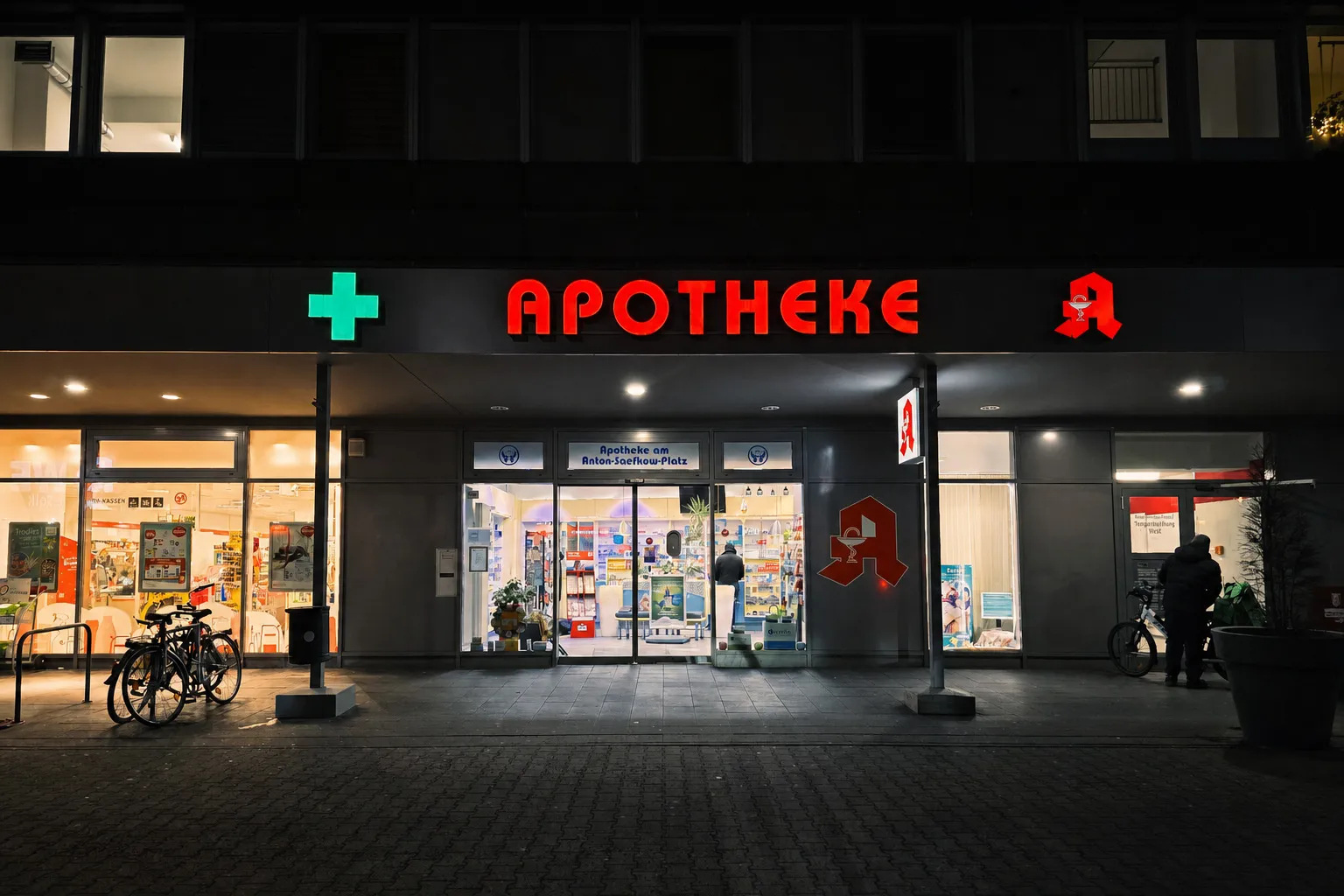 Die beleuchtete Fassade der Apotheke am Anton-Saefkow-Platz bei Nacht